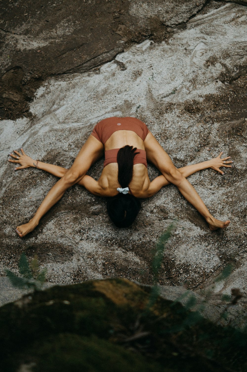 a woman laying on top of a rock next to a river