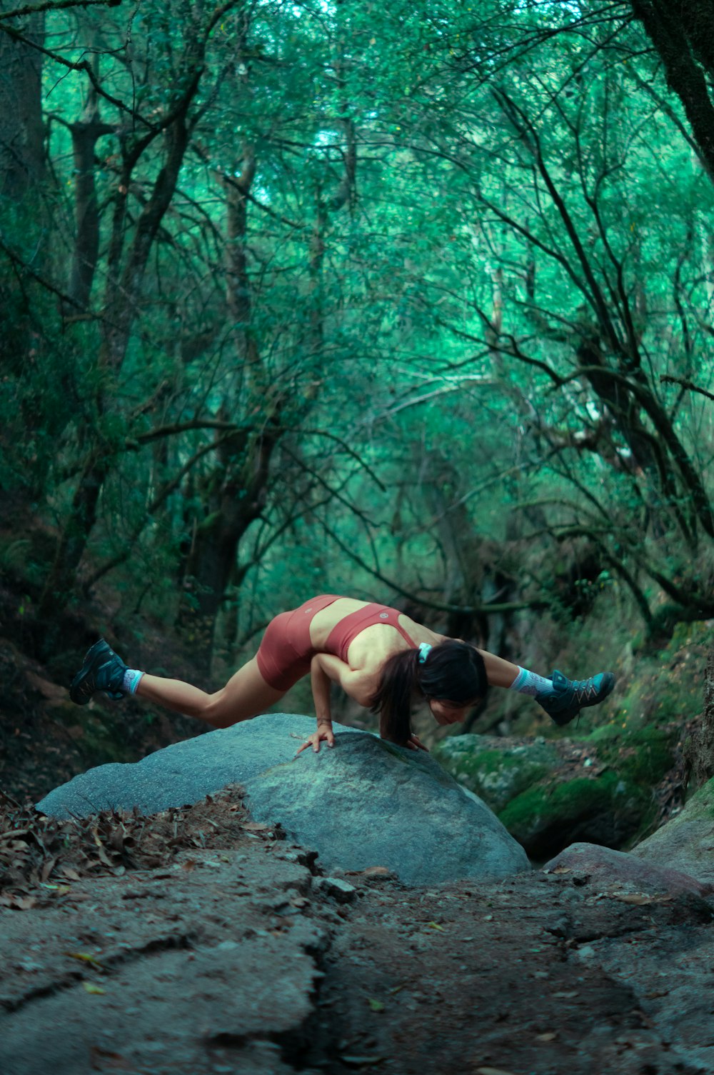 a woman is laying on a rock in the woods