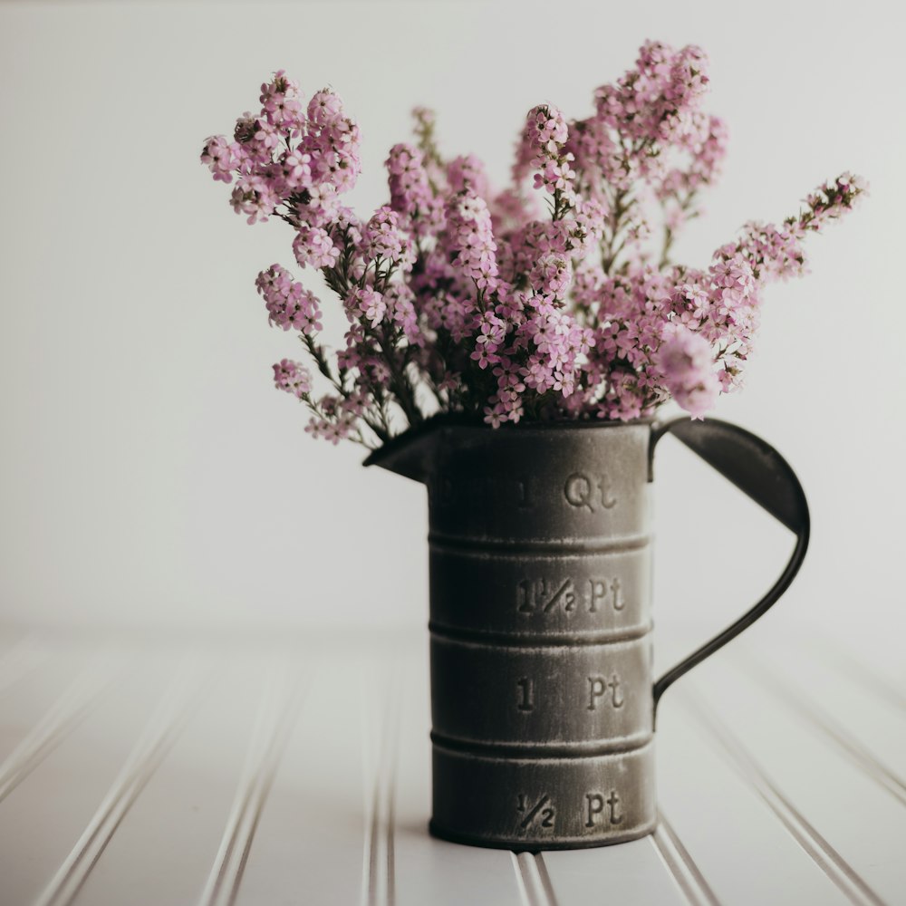 a watering can with flowers in it sitting on a table