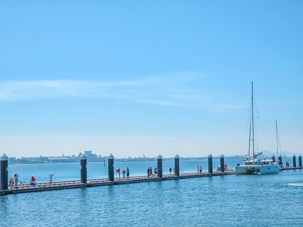 a group of people standing on a pier next to a boat