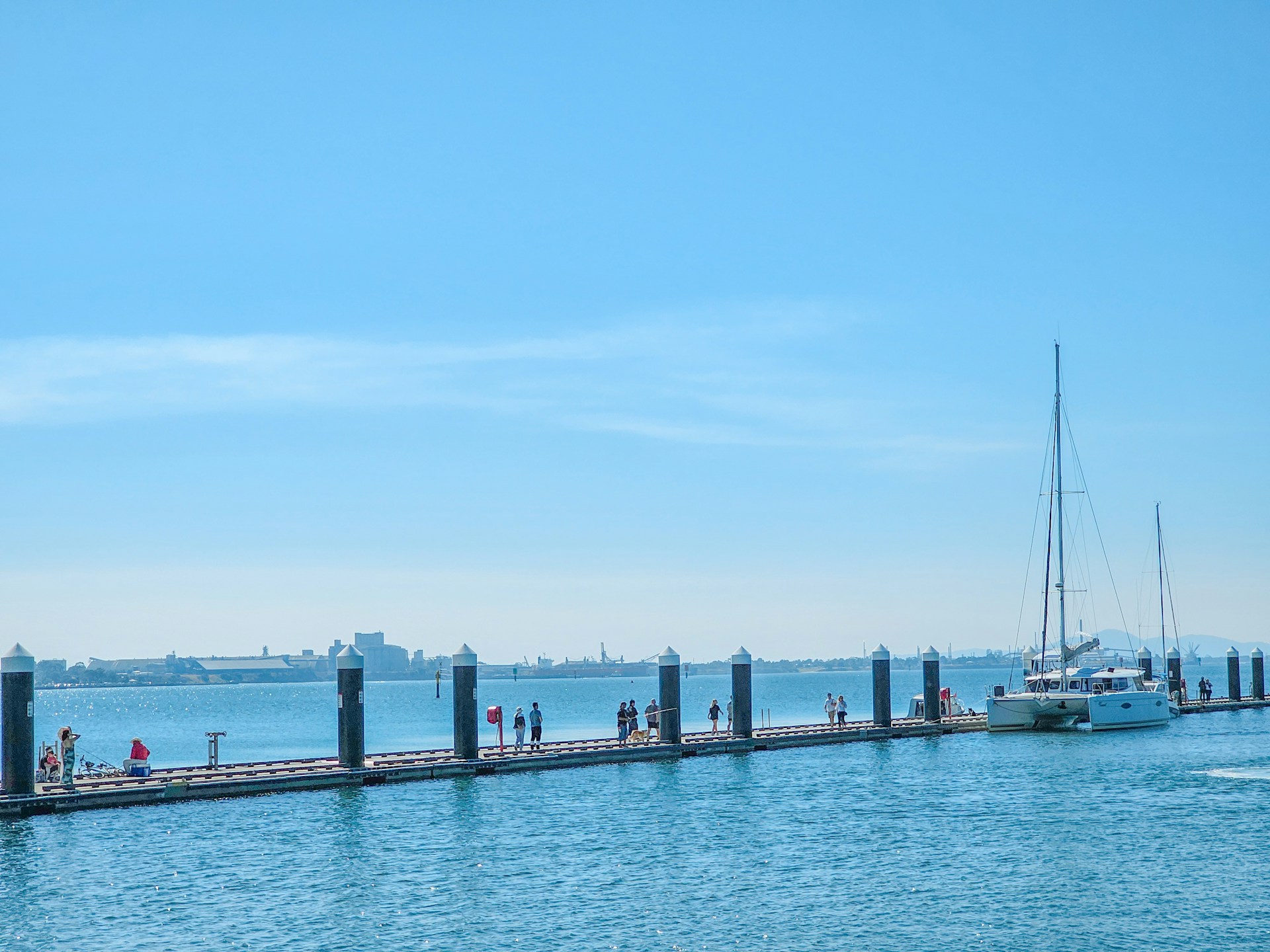 a group of people standing on a pier next to a boat