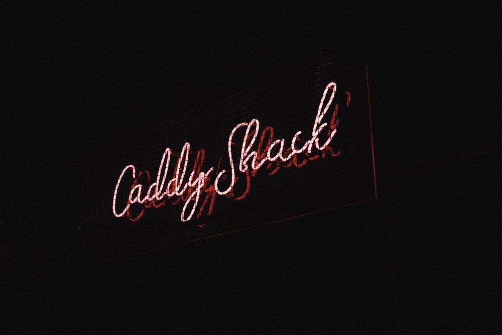 a red neon sign that reads caddy shack