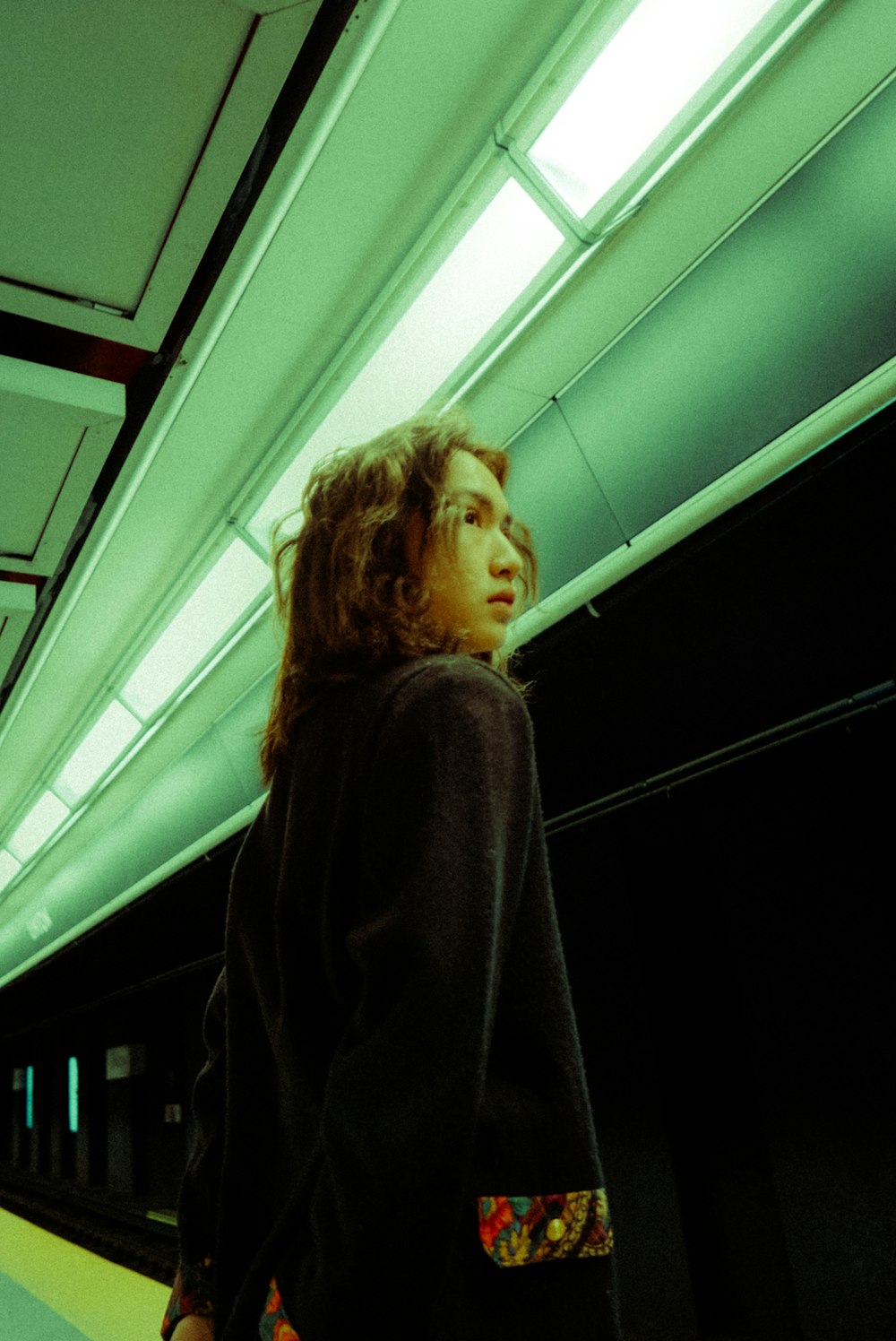 a woman standing on a subway platform in the dark