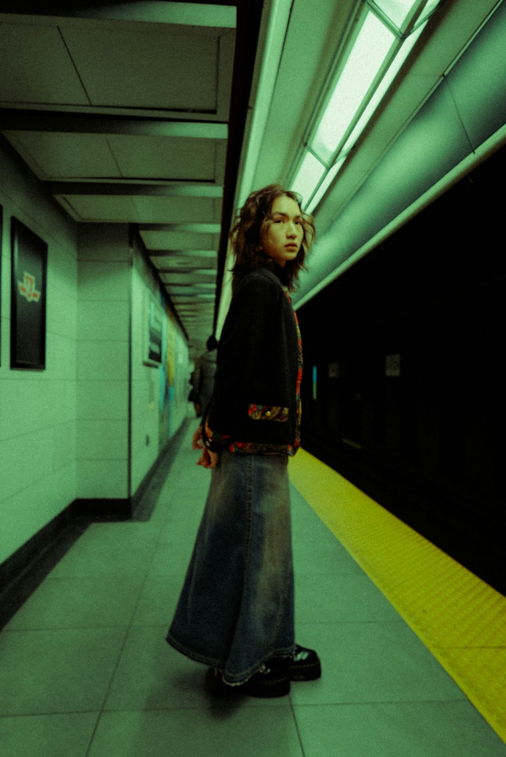 地下鉄のプラットホームで電車の横に立つ女性