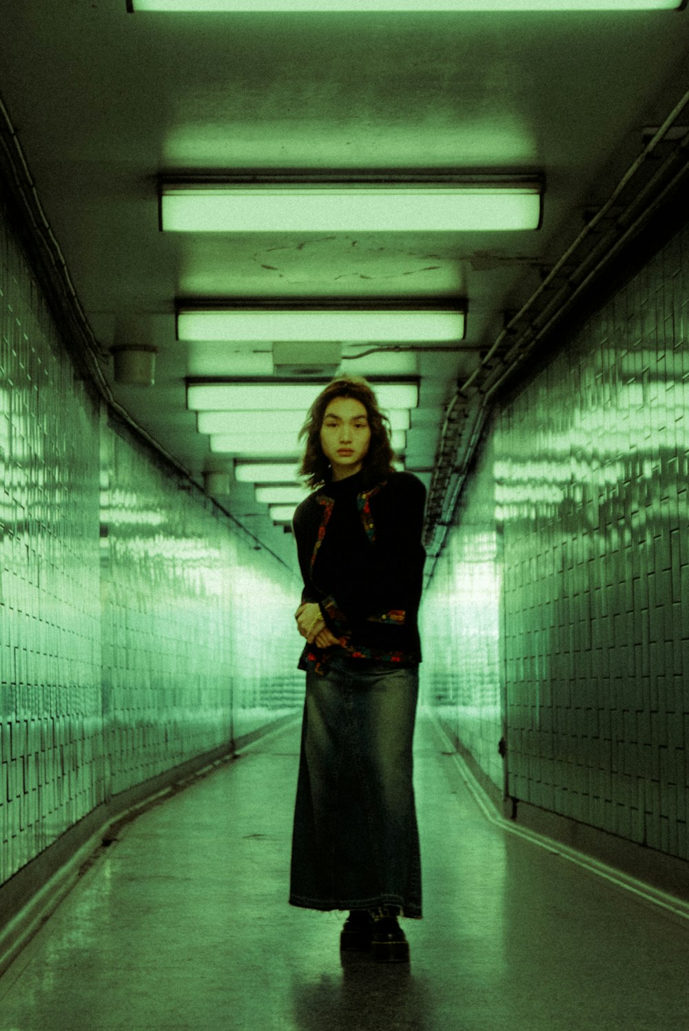 a woman is standing in a long hallway