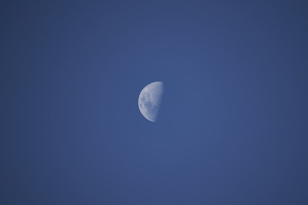 a half moon in a clear blue sky