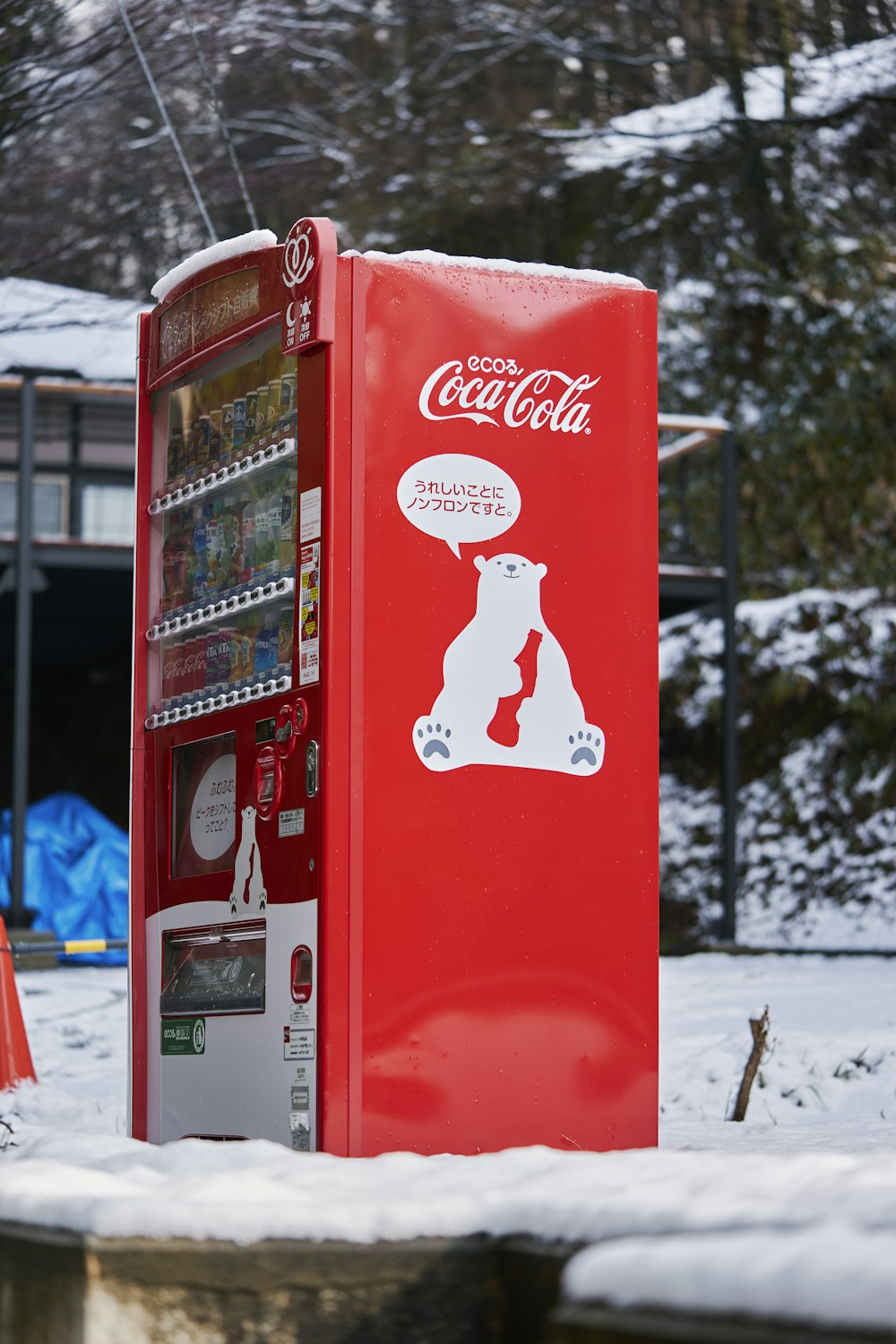 a coca - cola machine sitting on top of a snow covered ground