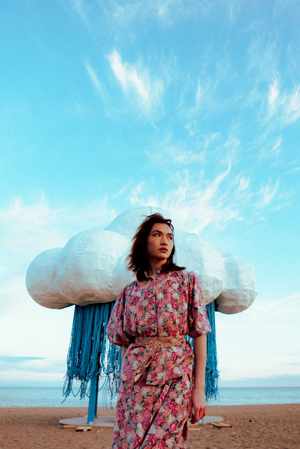una mujer de pie en una playa junto a una nube gigante