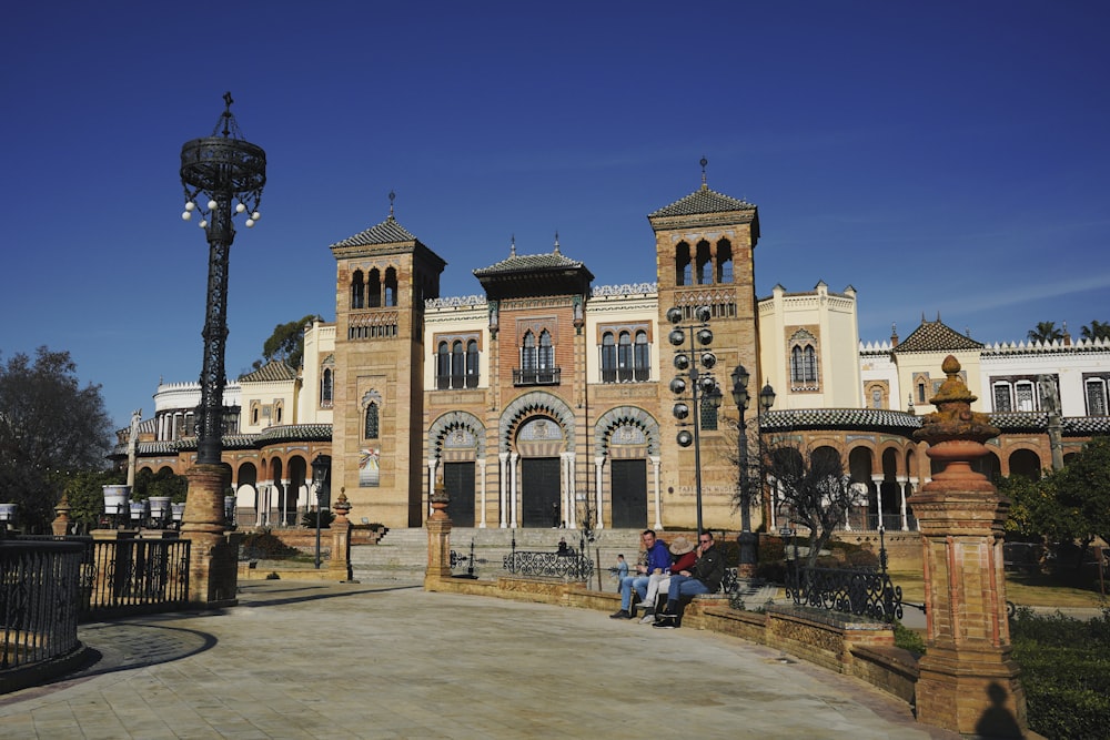 two people sitting on a bench in front of a large building