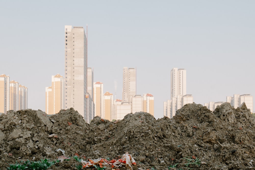 a large pile of dirt with a city in the background
