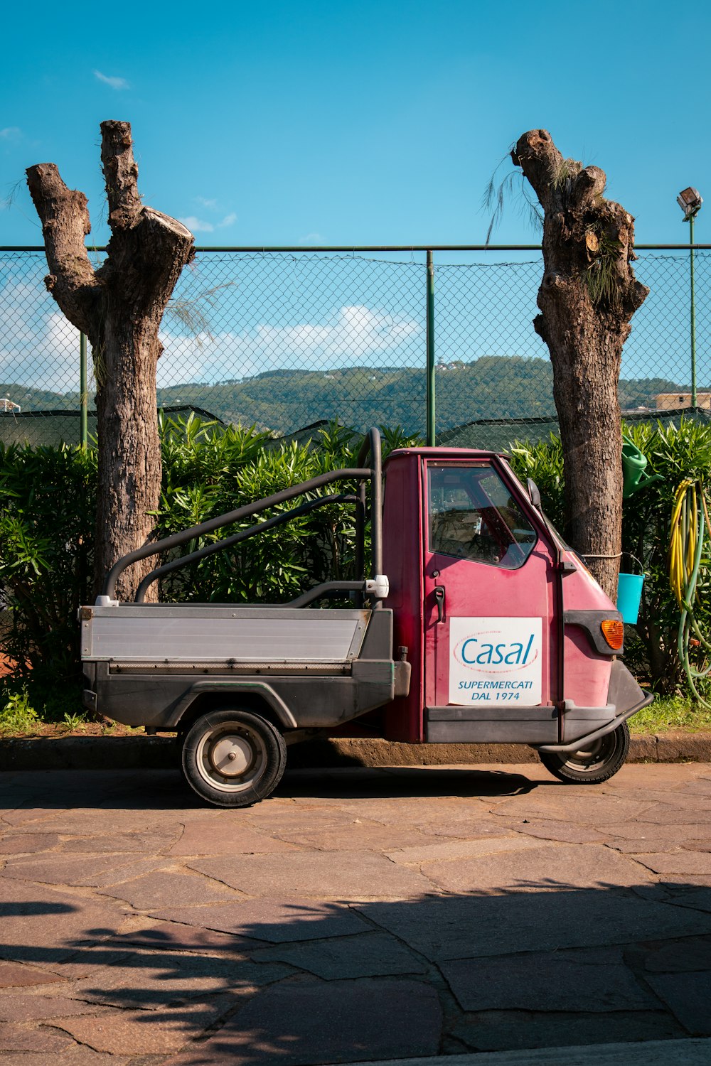 a pink truck parked in front of a fence