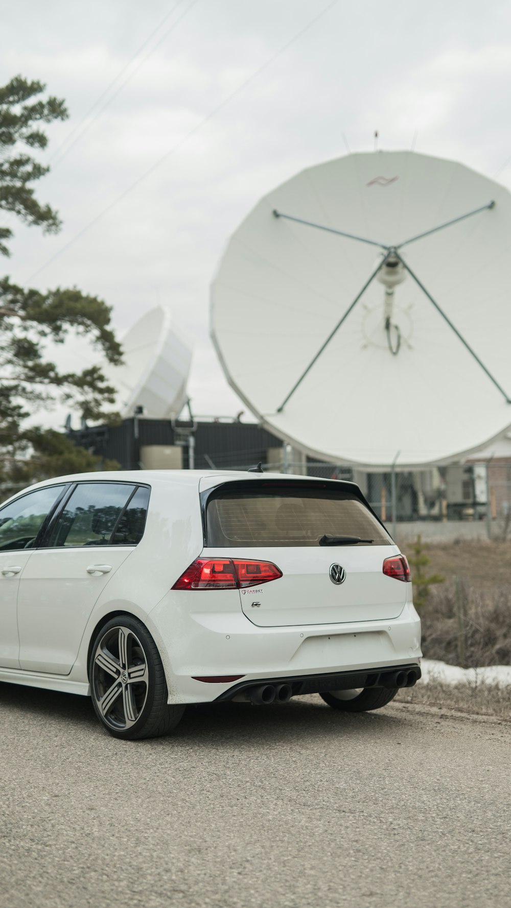 a white car parked in front of a satellite dish