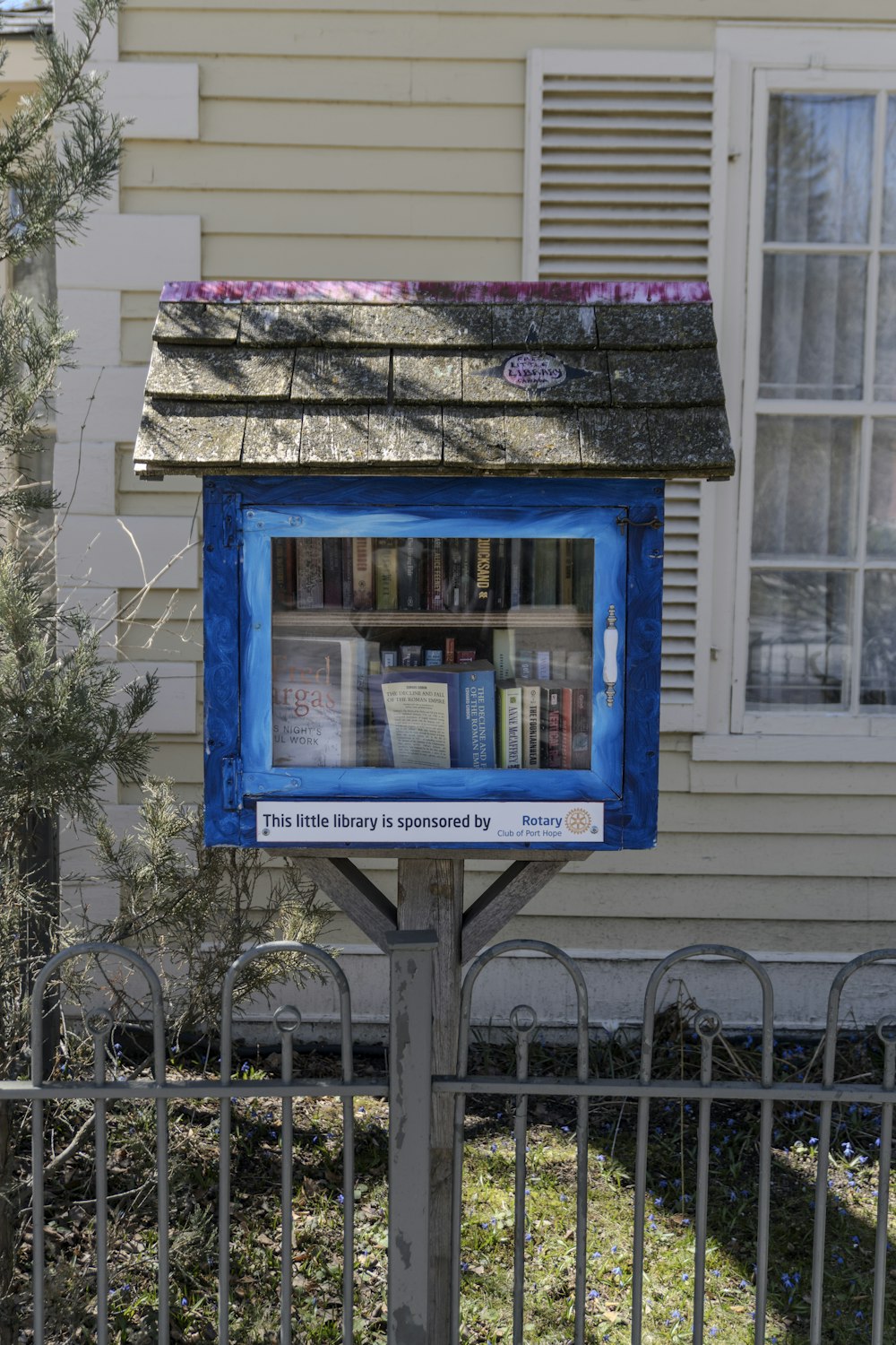 une boîte bleue sur un poteau devant une maison