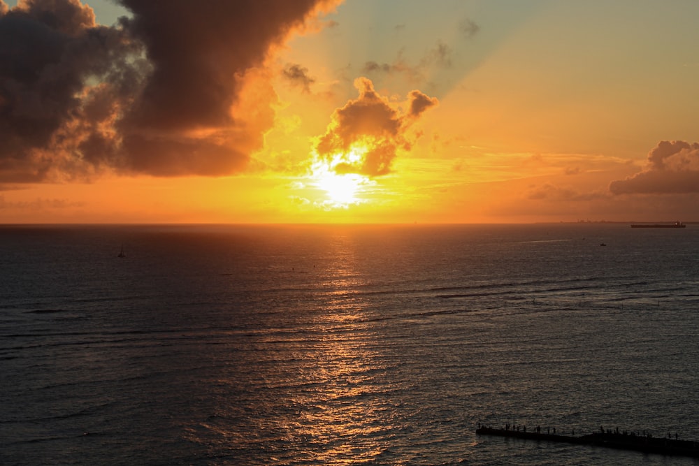 a large body of water with a sunset in the background