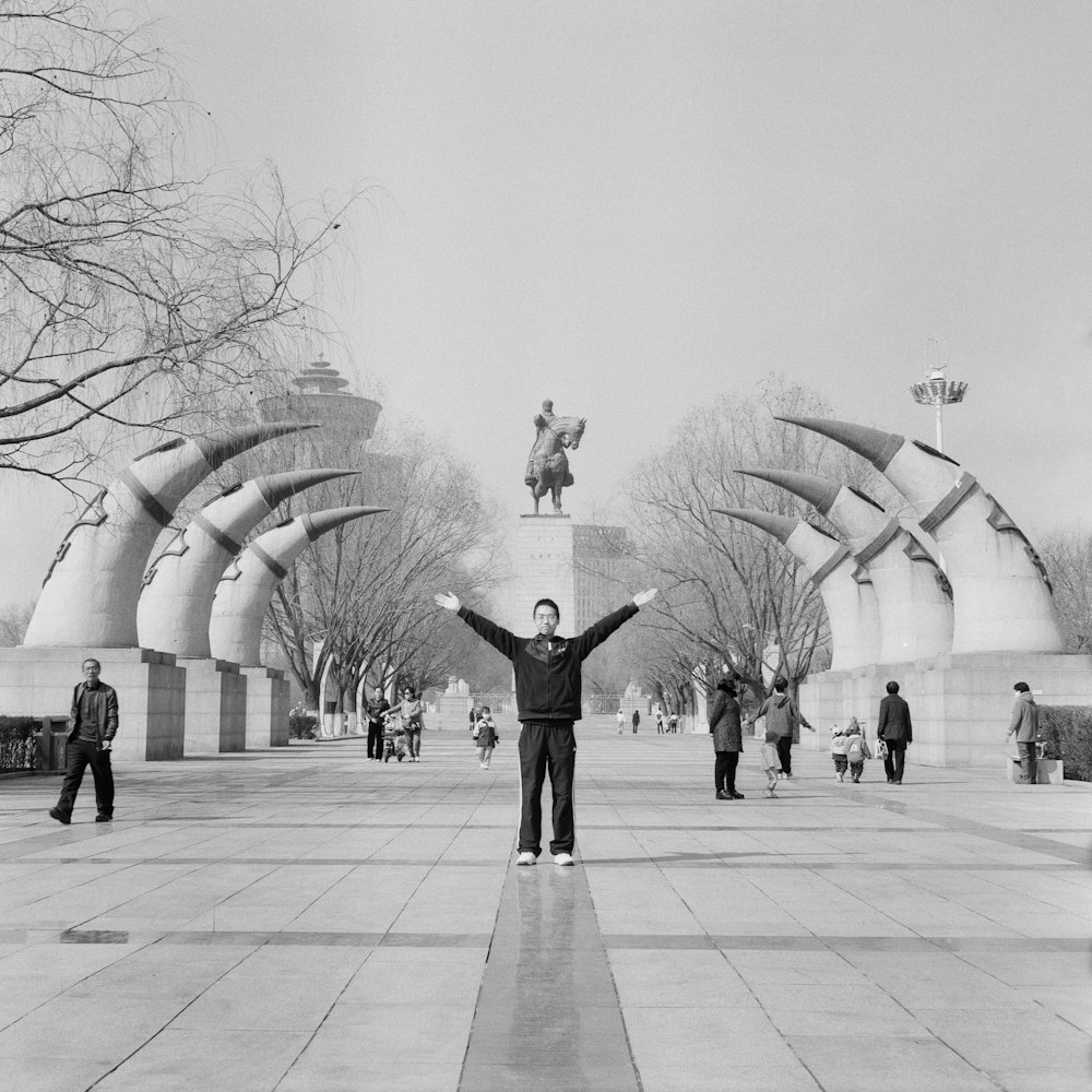 a man standing in a park with his arms wide open