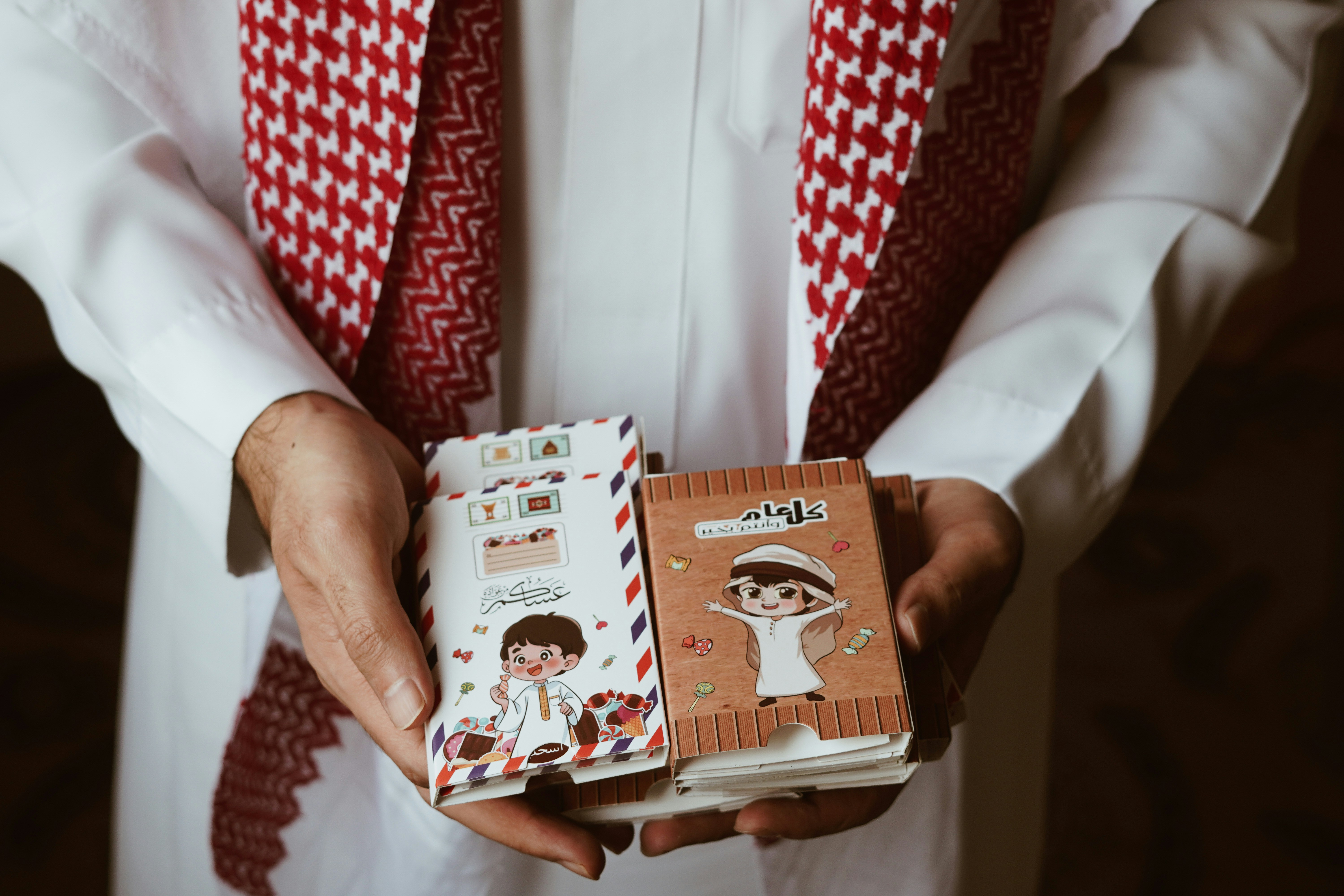a man in a white shirt and red tie holding two small books