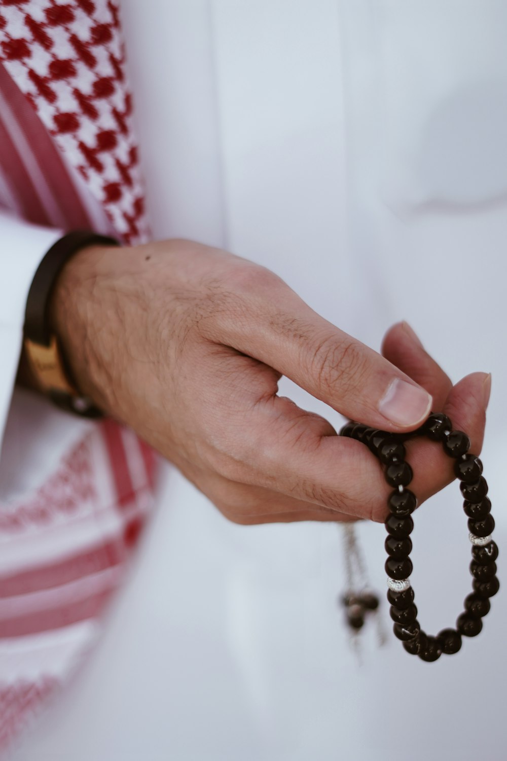 a man wearing a red and white tie holding a rosary