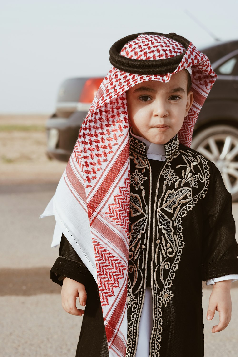 a young boy wearing a black and white outfit and a red and white scarf