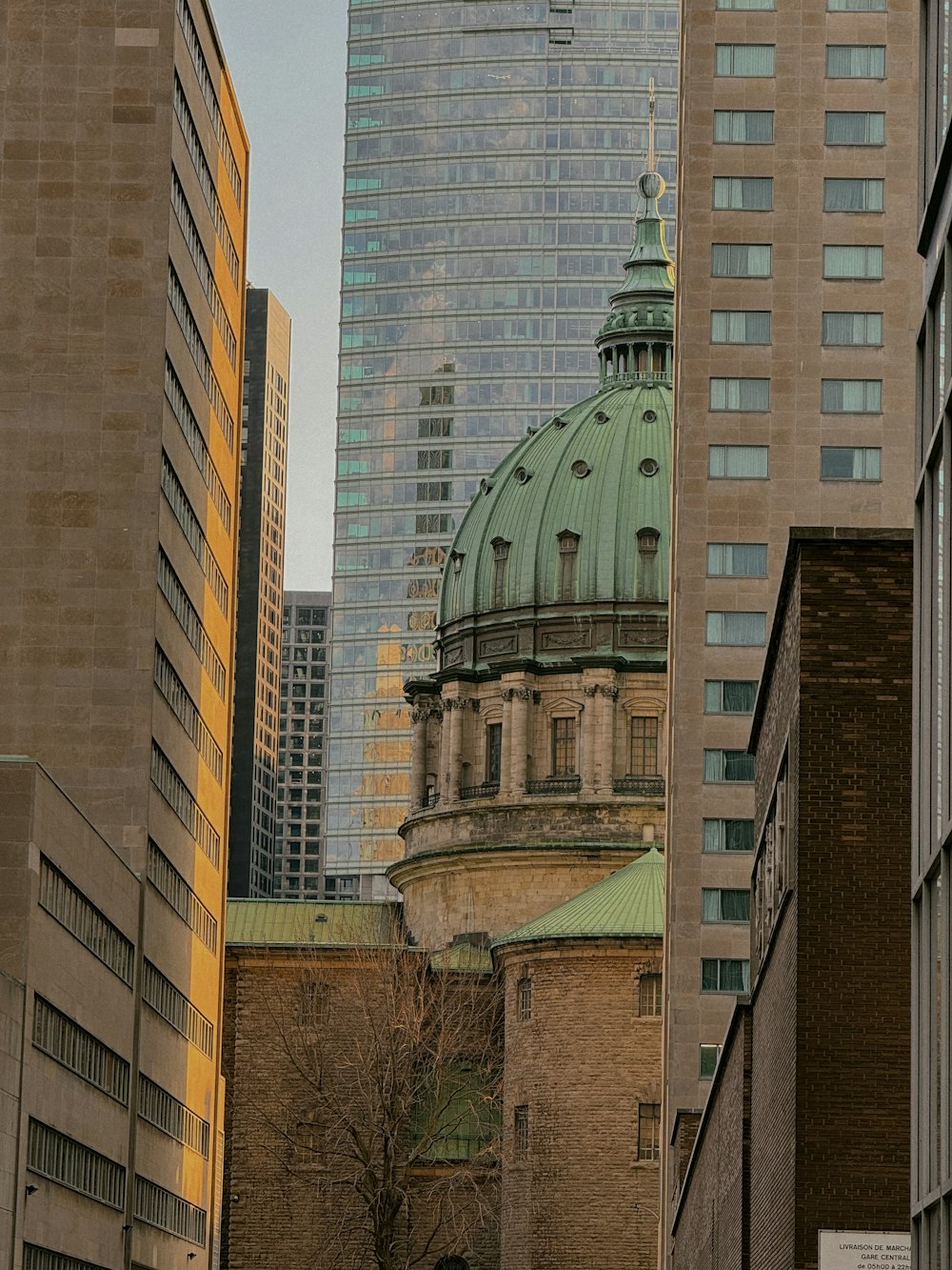 a tall building with a green dome in the middle of a city