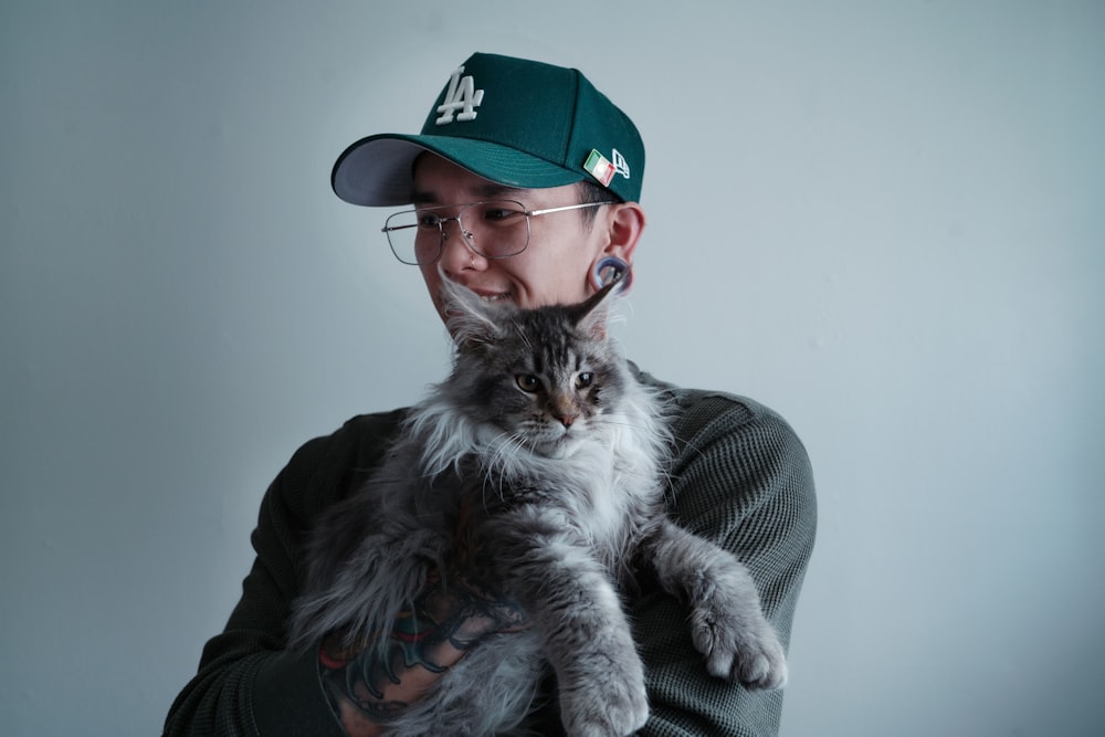 a man in a baseball cap holding a cat