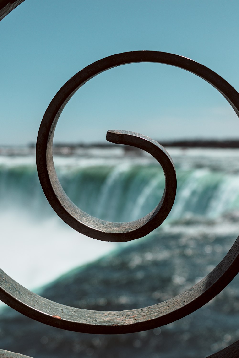 a close up of a metal object with a waterfall in the background