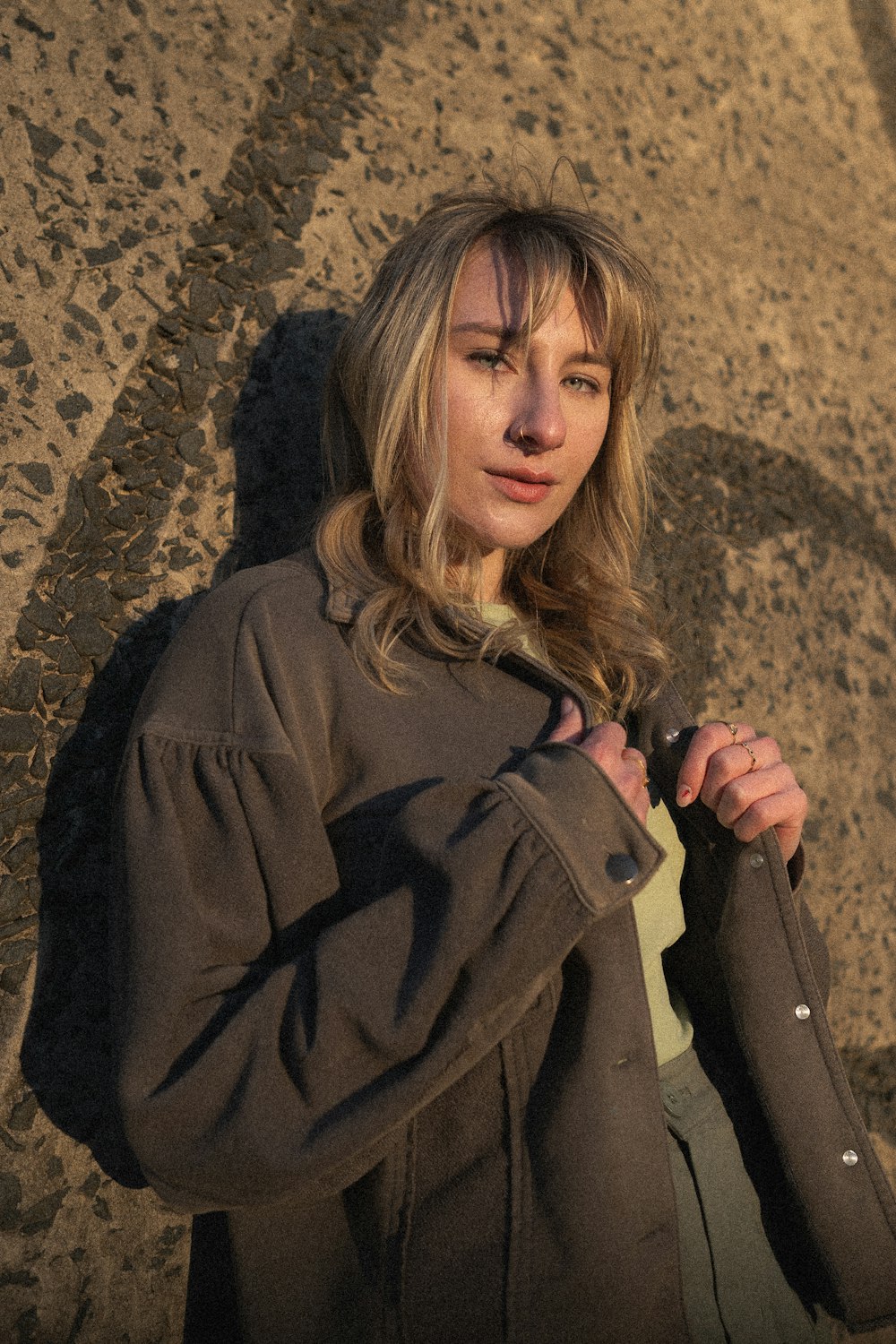 a woman is standing in the sand with a jacket on