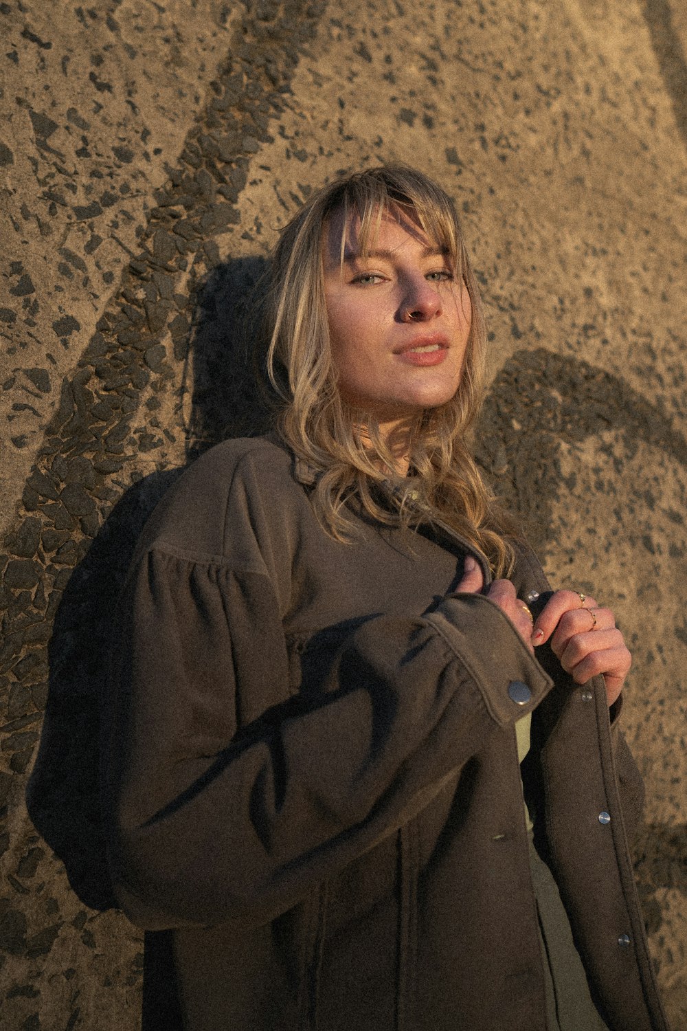 a woman standing in front of a rock wall