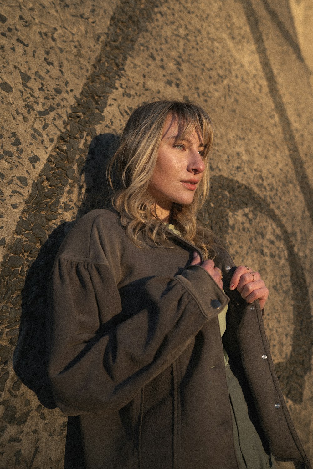 a woman standing in front of a wall with a jacket on