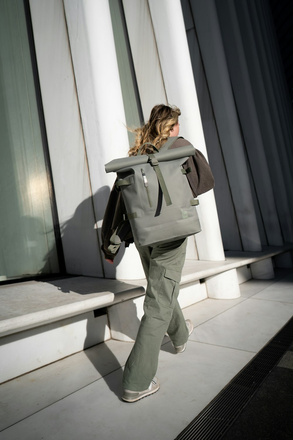 a woman walking down a sidewalk with a backpack on her back
