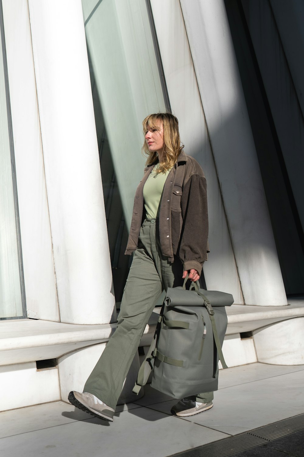 a woman walking down a sidewalk carrying a bag