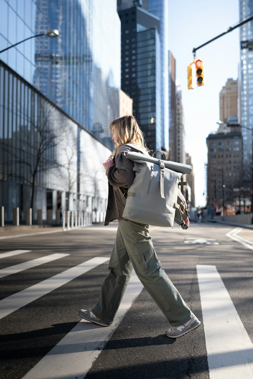 a woman walking across a cross walk in a city