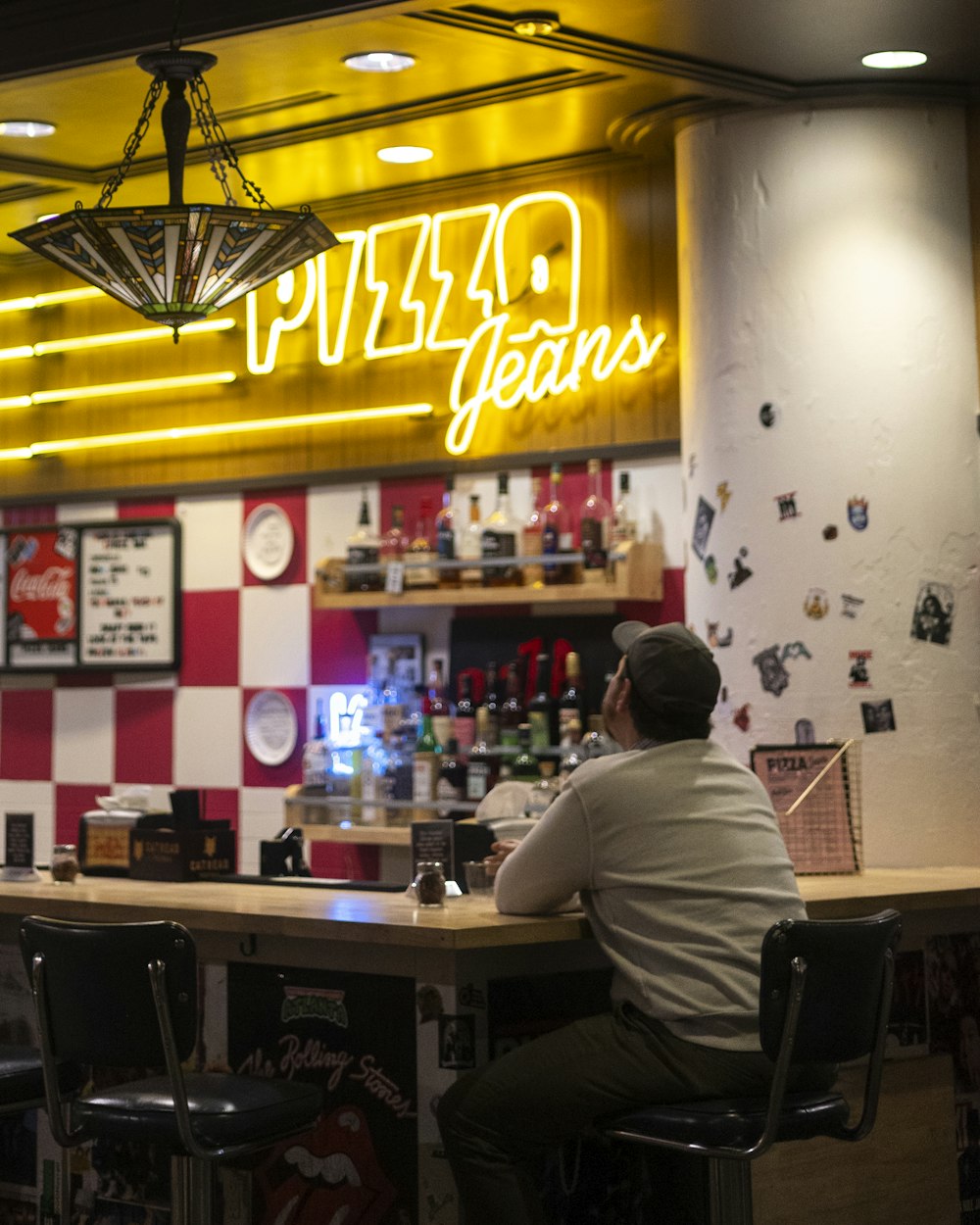 a man sitting at a bar in front of a neon sign