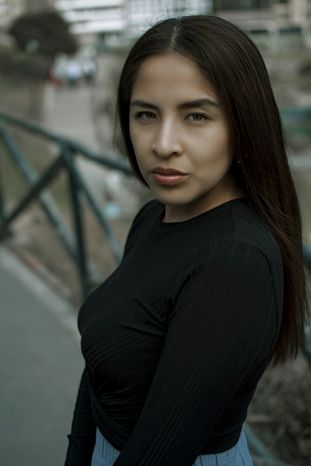 a woman with long hair standing in front of a railing