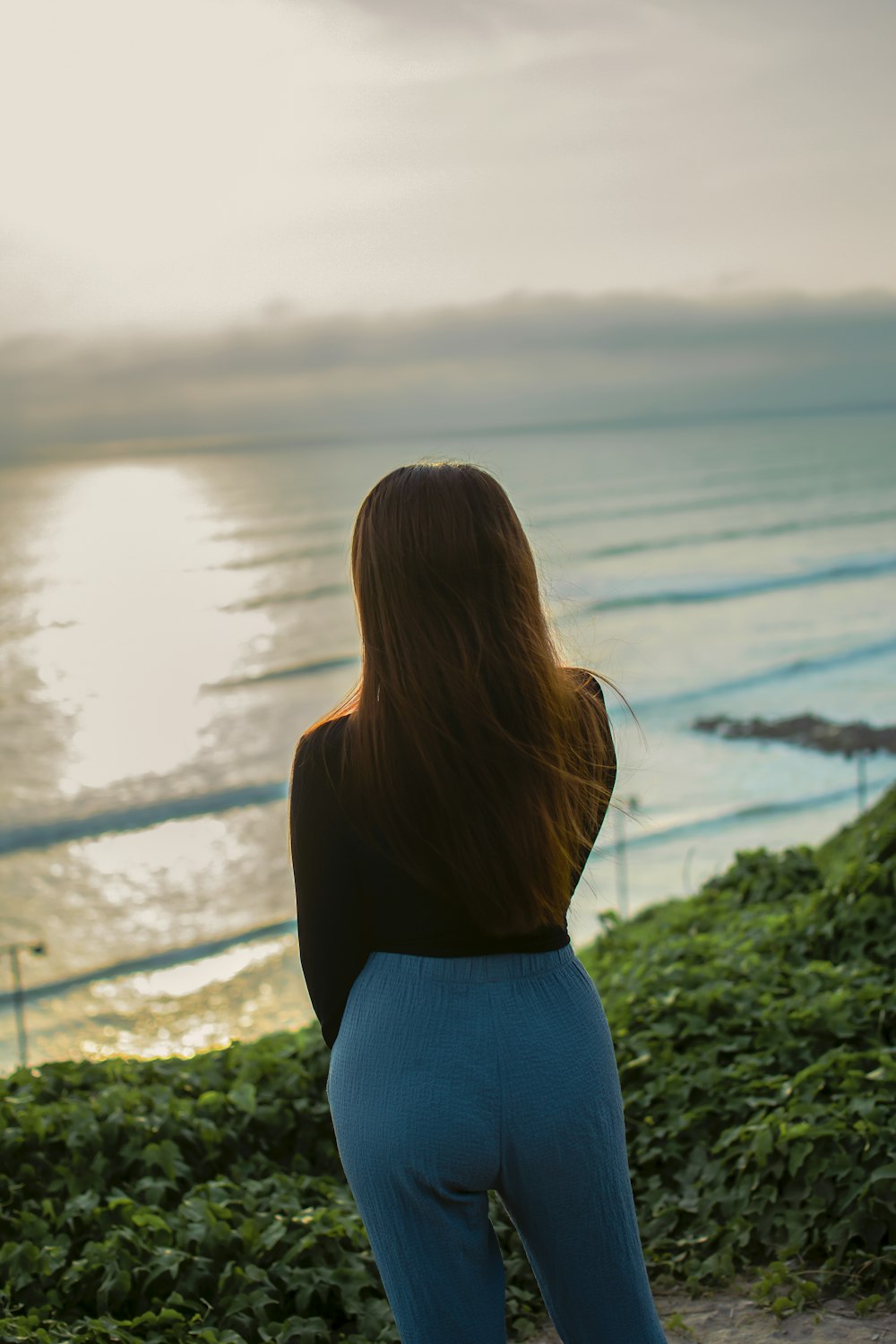 a woman standing on top of a lush green hillside