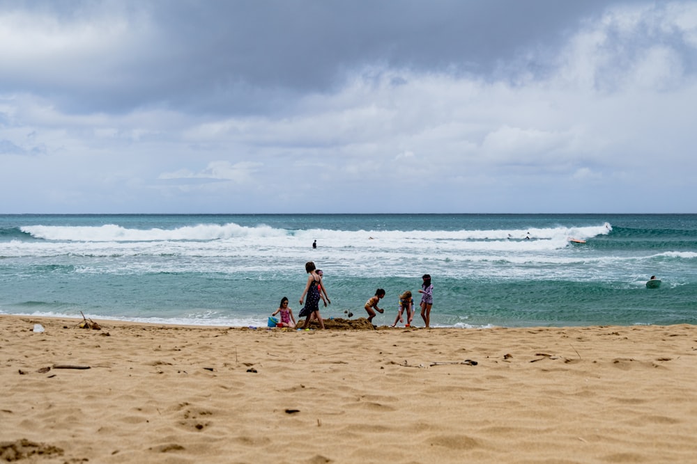 a group of people standing on top of a sandy beach