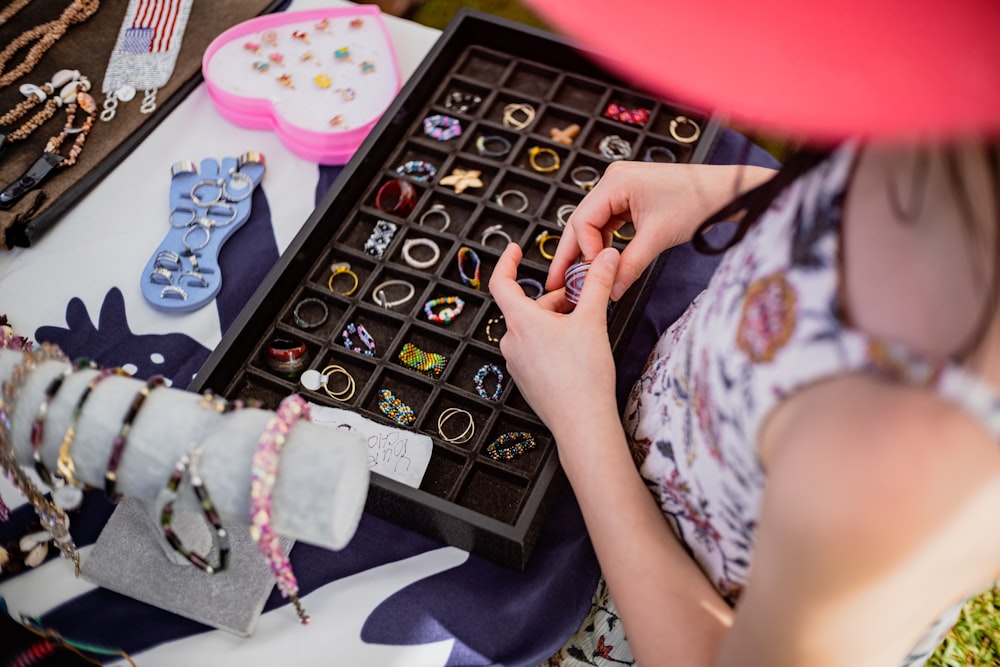 a woman sitting on the ground looking at a box of jewelry