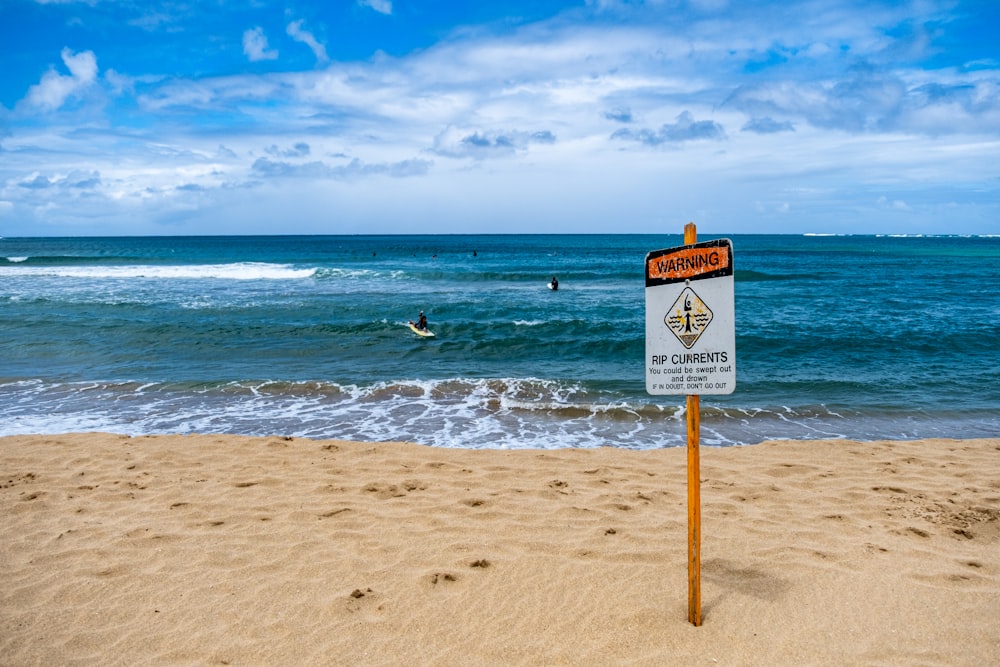 a sign that is on the sand near the water