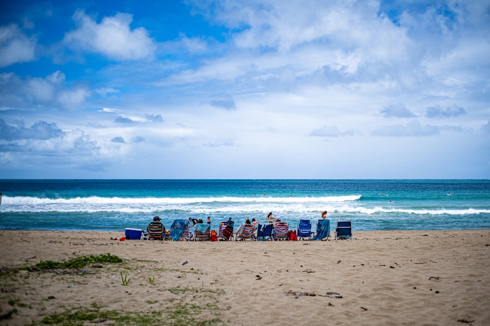 a group of people sitting on top of a sandy beach