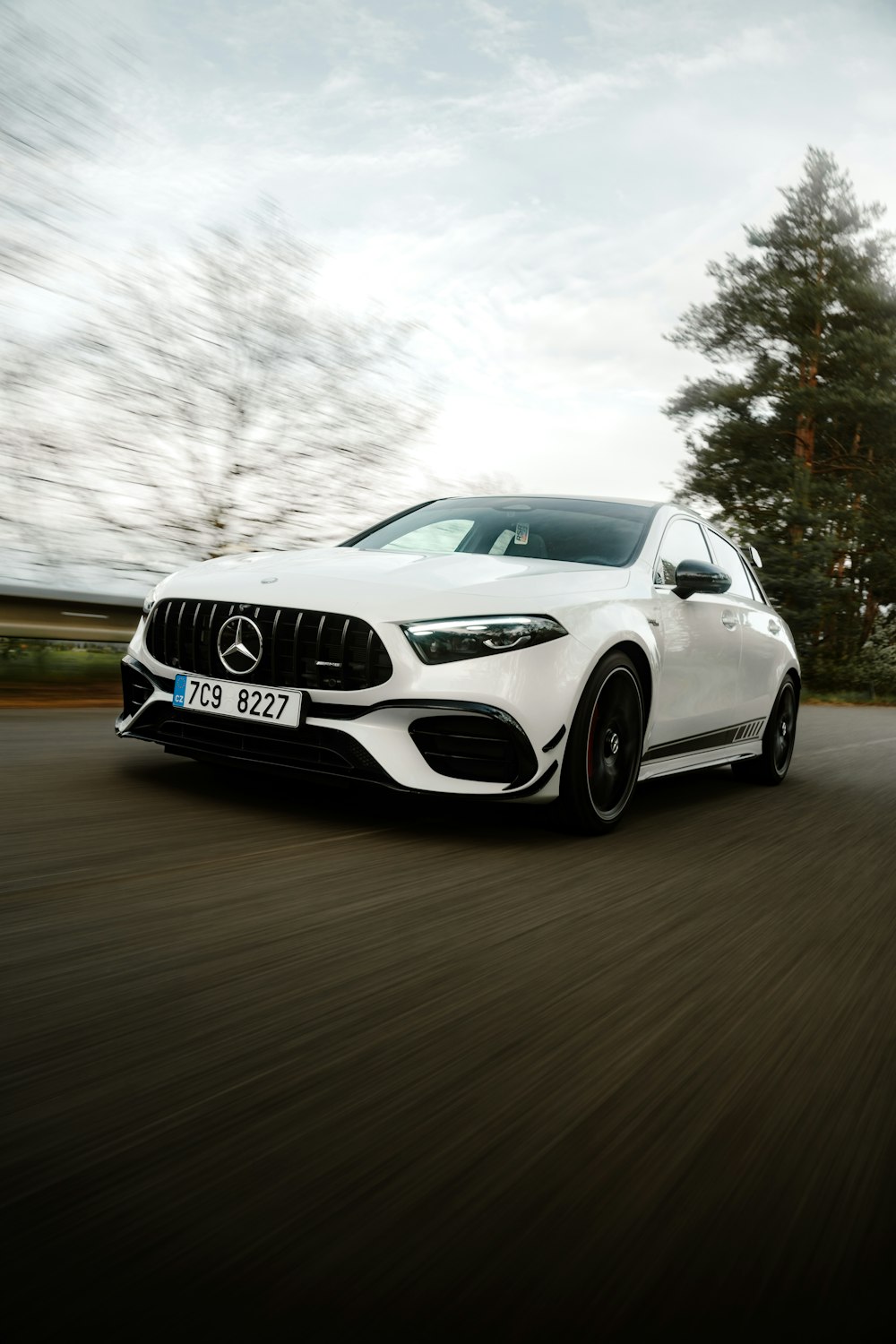 a white mercedes cla driving down a road