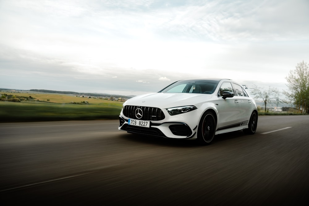 a white mercedes cla driving down a road