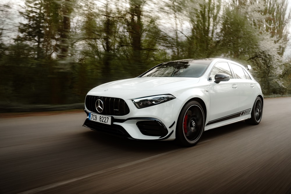 a white mercedes cla driving down a road