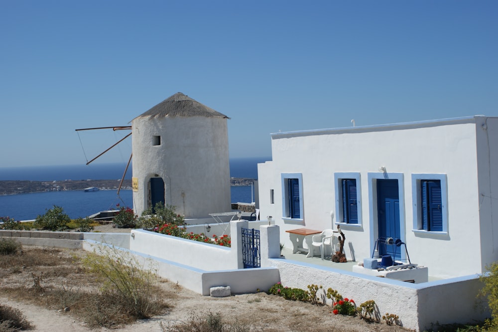 a white house with blue shutters and a windmill in the background