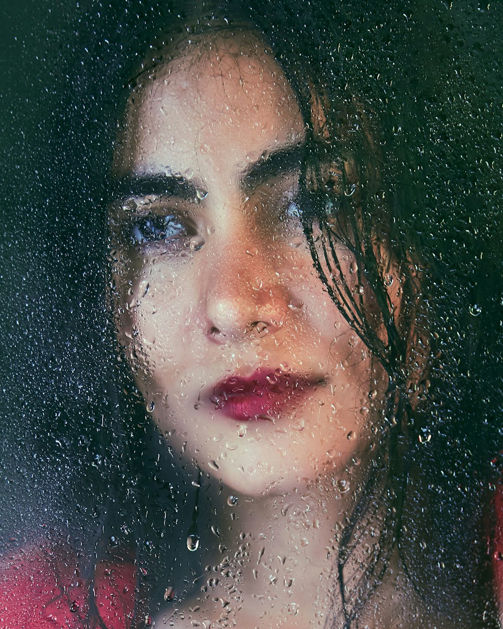 a woman looking out a window in the rain