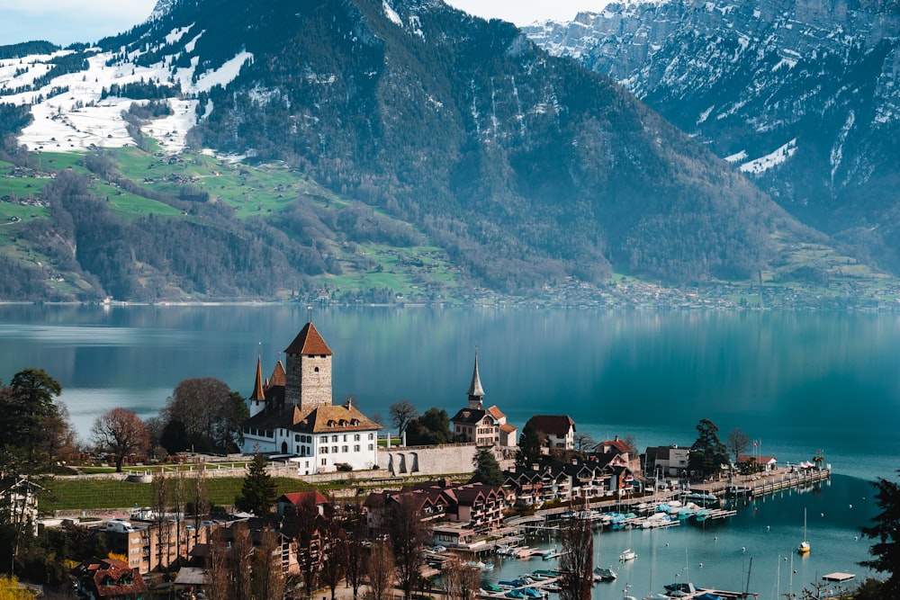 a scenic view of a lake with a church and mountains in the background