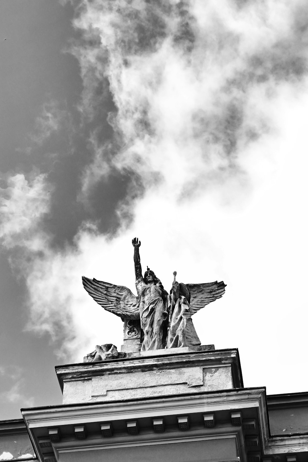 a black and white photo of a statue on top of a building