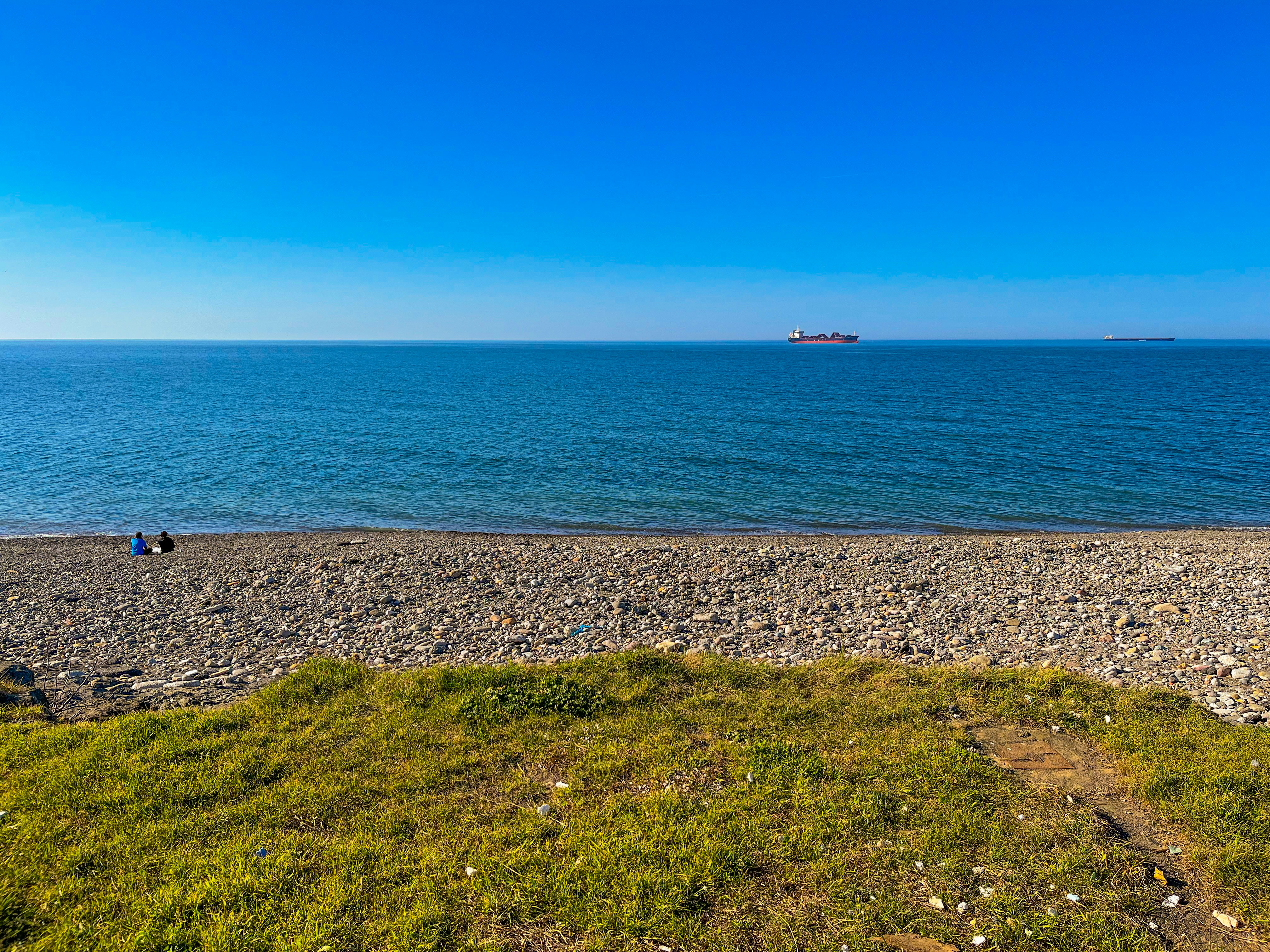a couple of people sitting on top of a sandy beach