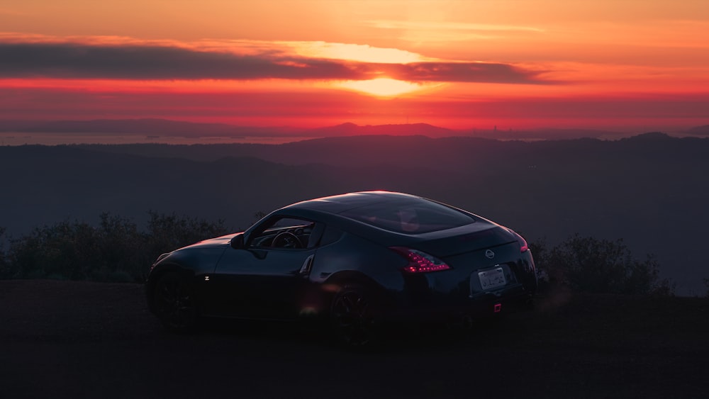 a black sports car parked in front of a sunset
