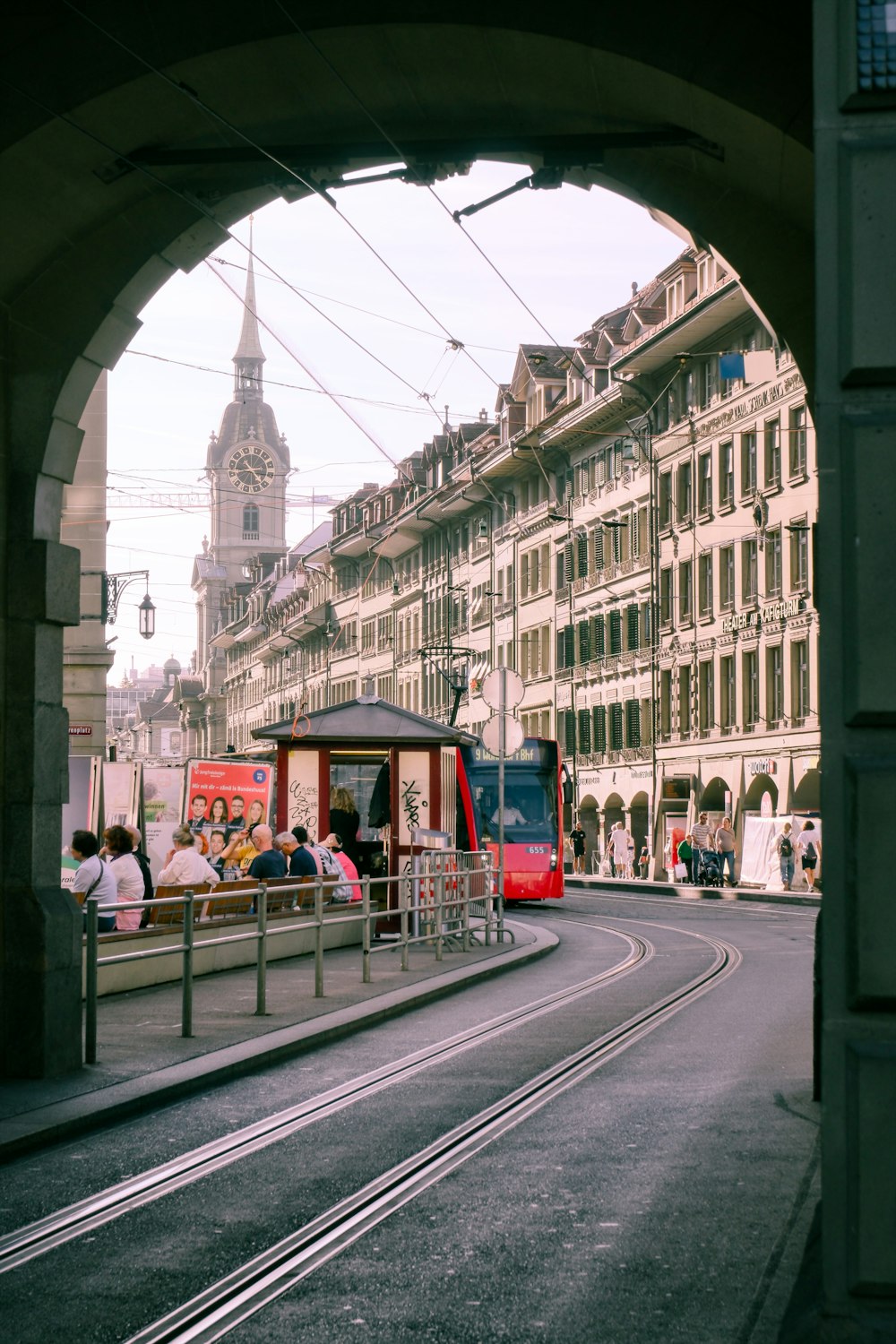 a red train traveling down train tracks next to tall buildings