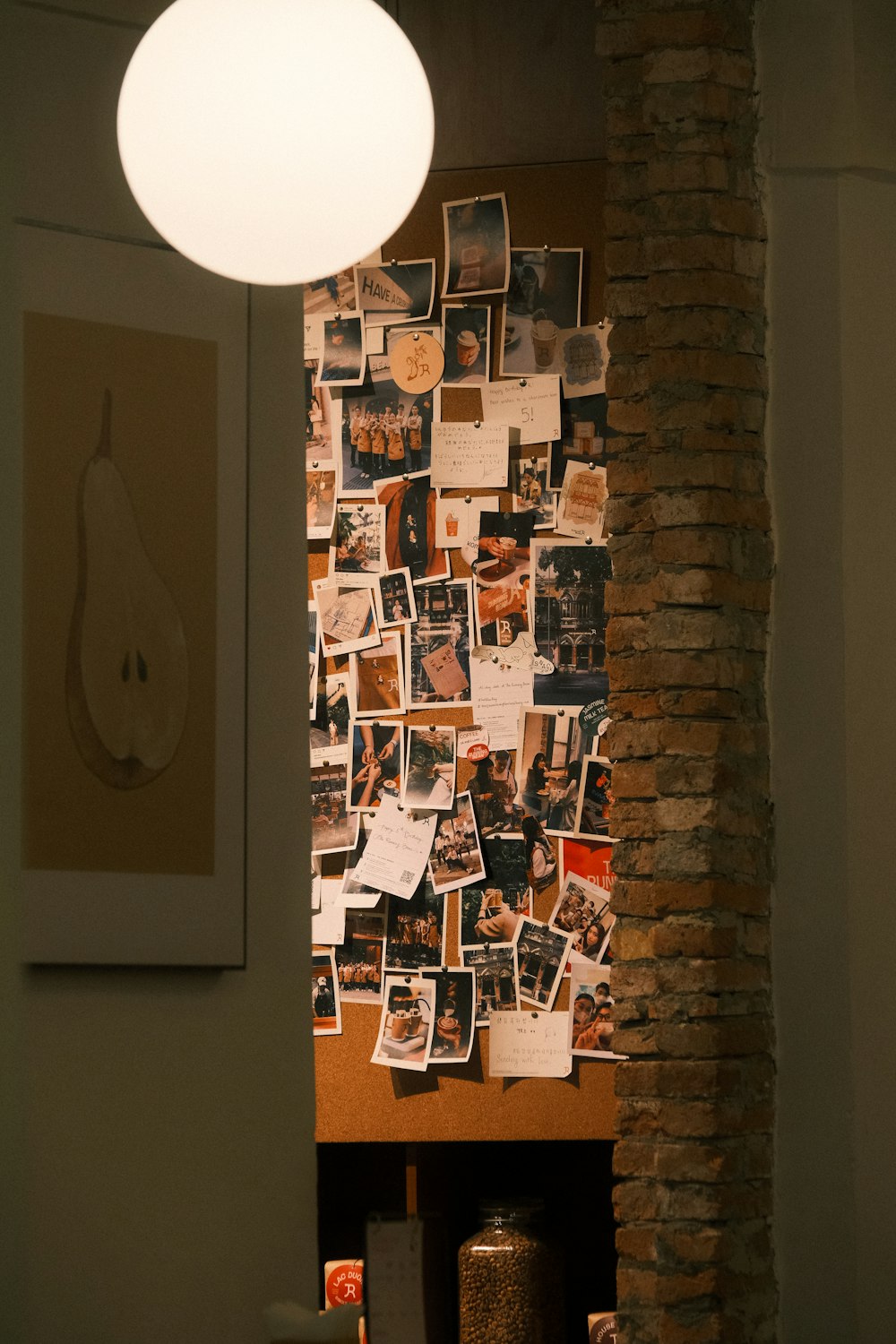a wall covered in pictures and pictures next to a lamp