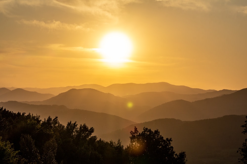 the sun is setting over a mountain range